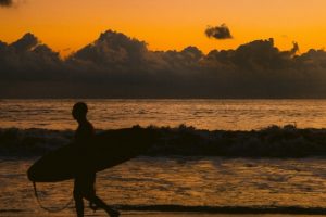 Man with surfboard in a sunset on the beach